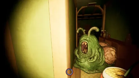 Monstruo verde con antenas asomando por una puerta, iluminado con linterna